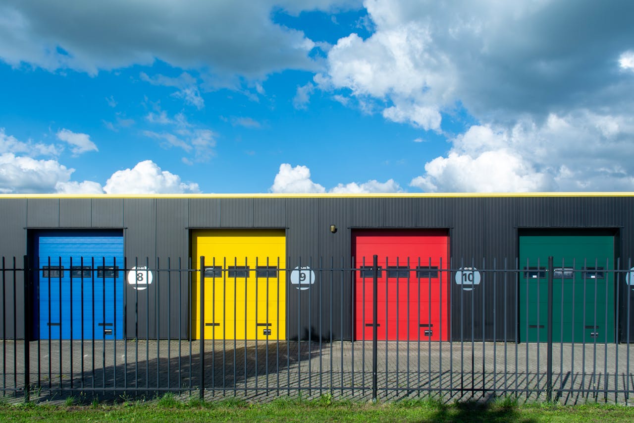 Vibrant garage doors in primary colors contrast with a bright blue sky. Modern industrial style.