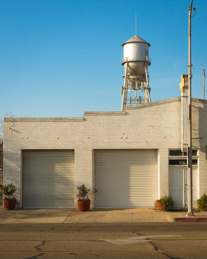 Facade of small industrial brick building with water tower on roof on sunny day